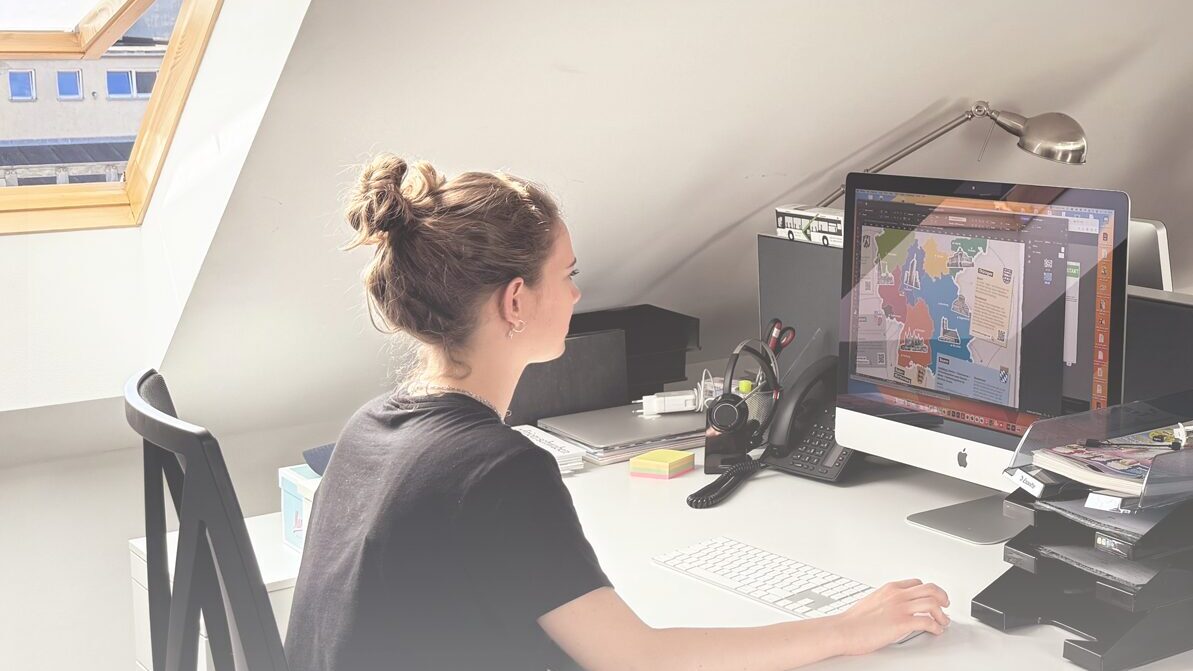 Zwei Frauen, die an gegenüberstehenden Schreibtischen in einem Büro sitzen an Computern arbeiten